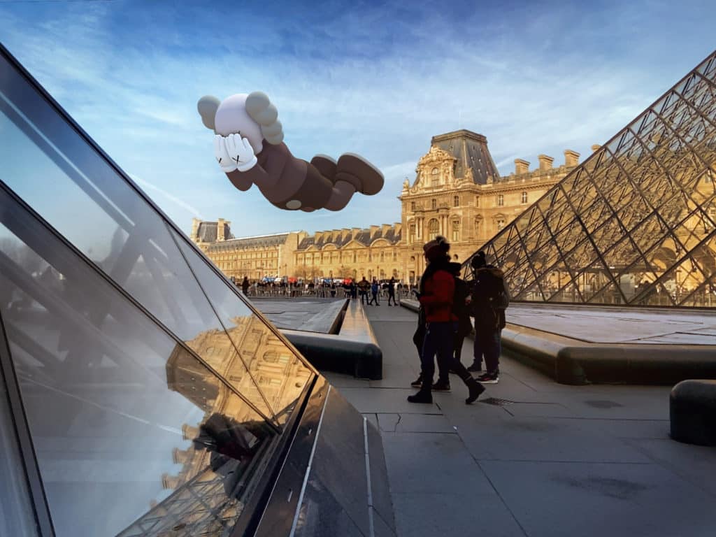 KAWS AR Art Sculptures hovering over the Louvre Pyramids in Paris.